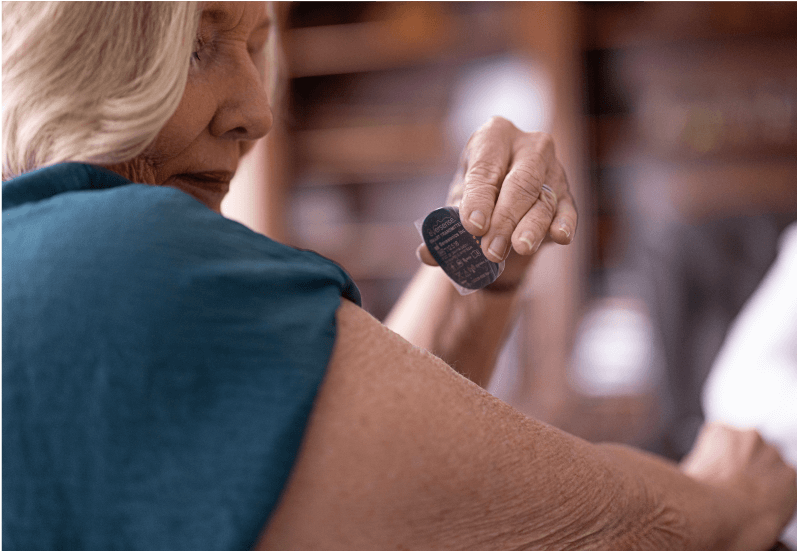 Eversense users applies the Eversense 365 Smart Transmitter to upper arm in a cozy, home setting. 